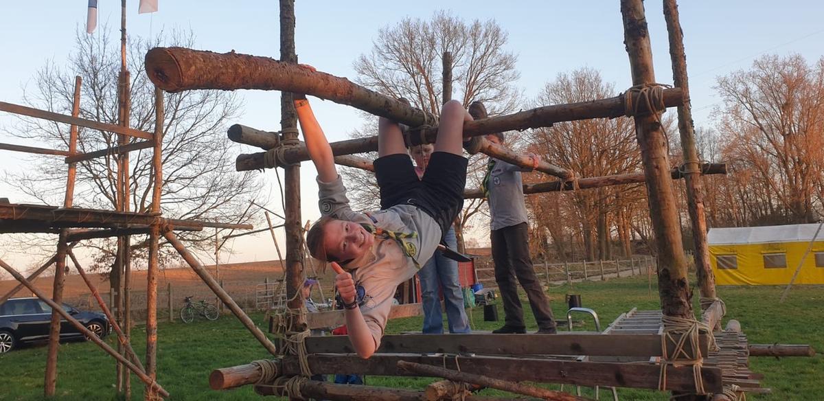 Ein junger Mensch in Pfadfinderuniform klettert am Holz-Klettergerüst