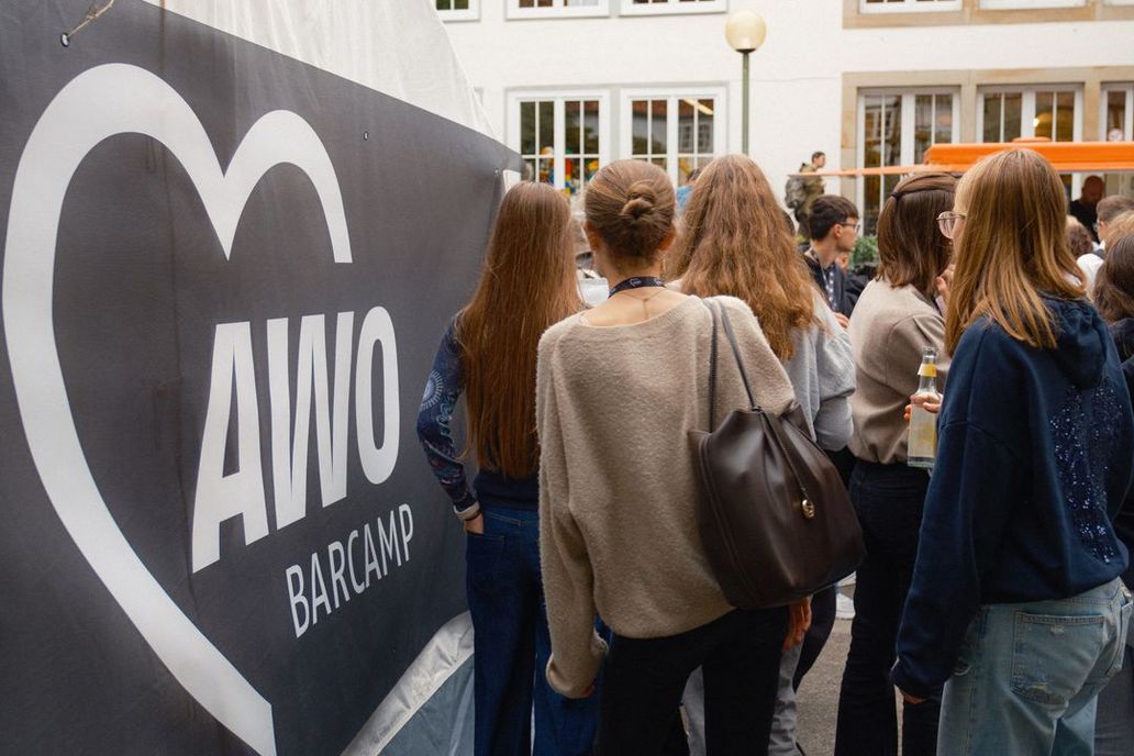 Teilnehmer*innen des AWO Barcamp am Eingang, vor einem AWO Banner